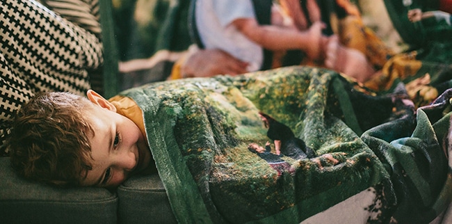 child on a sofa covering with a customised Photo Blanket