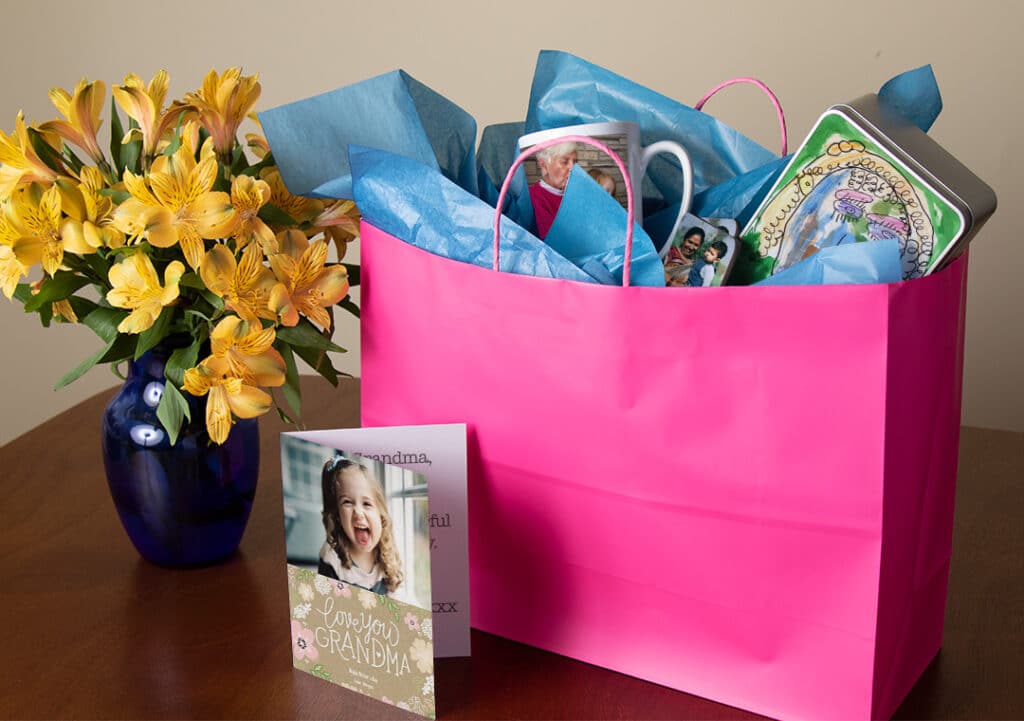 Flowers in vase, large gift bag, blank card on table