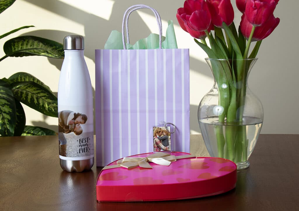 Bottle, gift bag, flowers in vase, box of chocolates