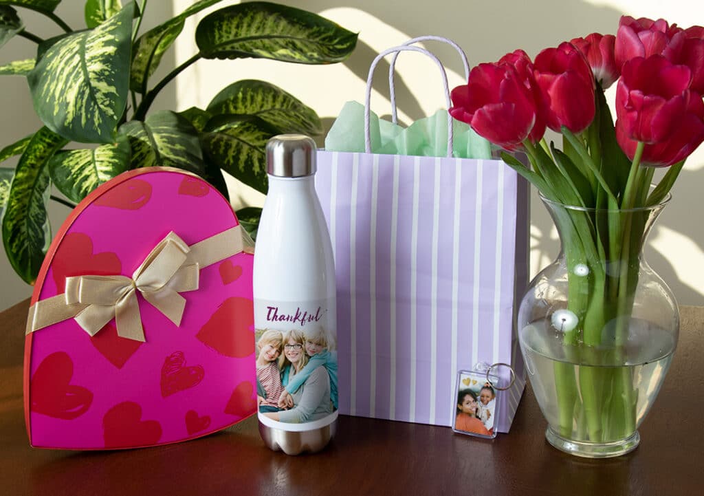Bottle, gift bag, flowers in vase, box of chocolates
