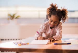 Cute little girl coloring at table