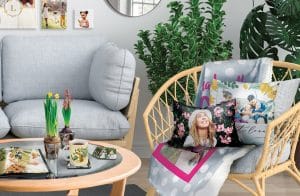 living room with pillows, blanket on chair, canvas on wall, photo boook, plant pot, coasters and mug on table.