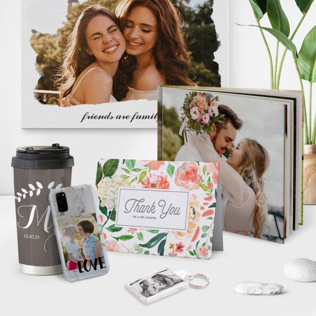 A set of photo gifts offered by Snapfish, a lovely canvas, photo book, key ring, travel mug, phone case and a card placed on a desk.