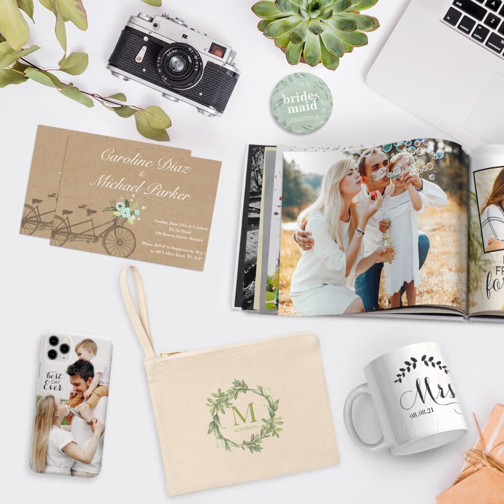 A collage of products offered by Snapfish, an open photo book, personalized card, custom canvas pouch, fun custom button pin and mug presented on a surface with a camera and a laptop.