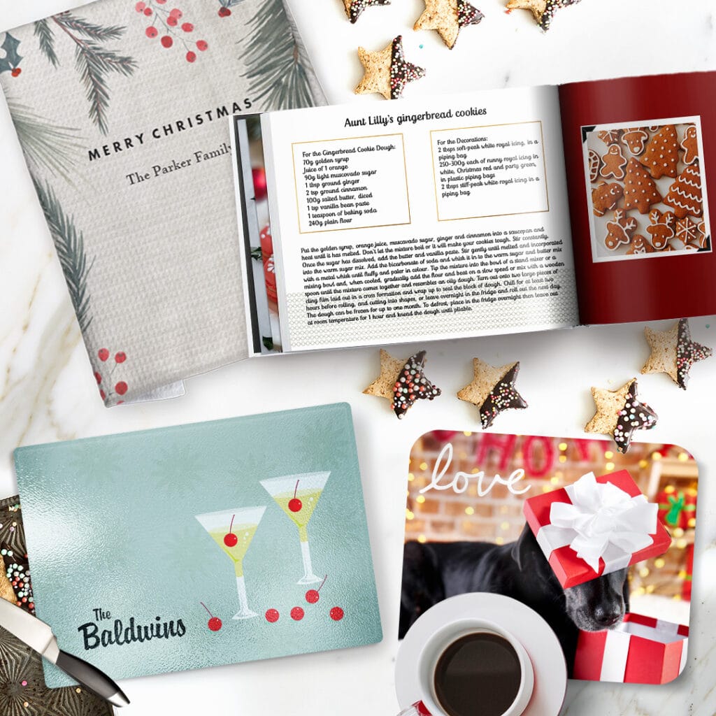 a personalised recipe photo book, a chopping board, tea towel and a placemat placed on a kitchen counter with star cookies on it