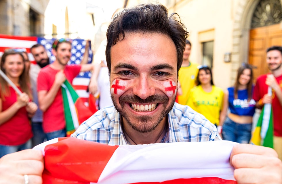 a photo of a cheering football fan with face paint on his cheeks