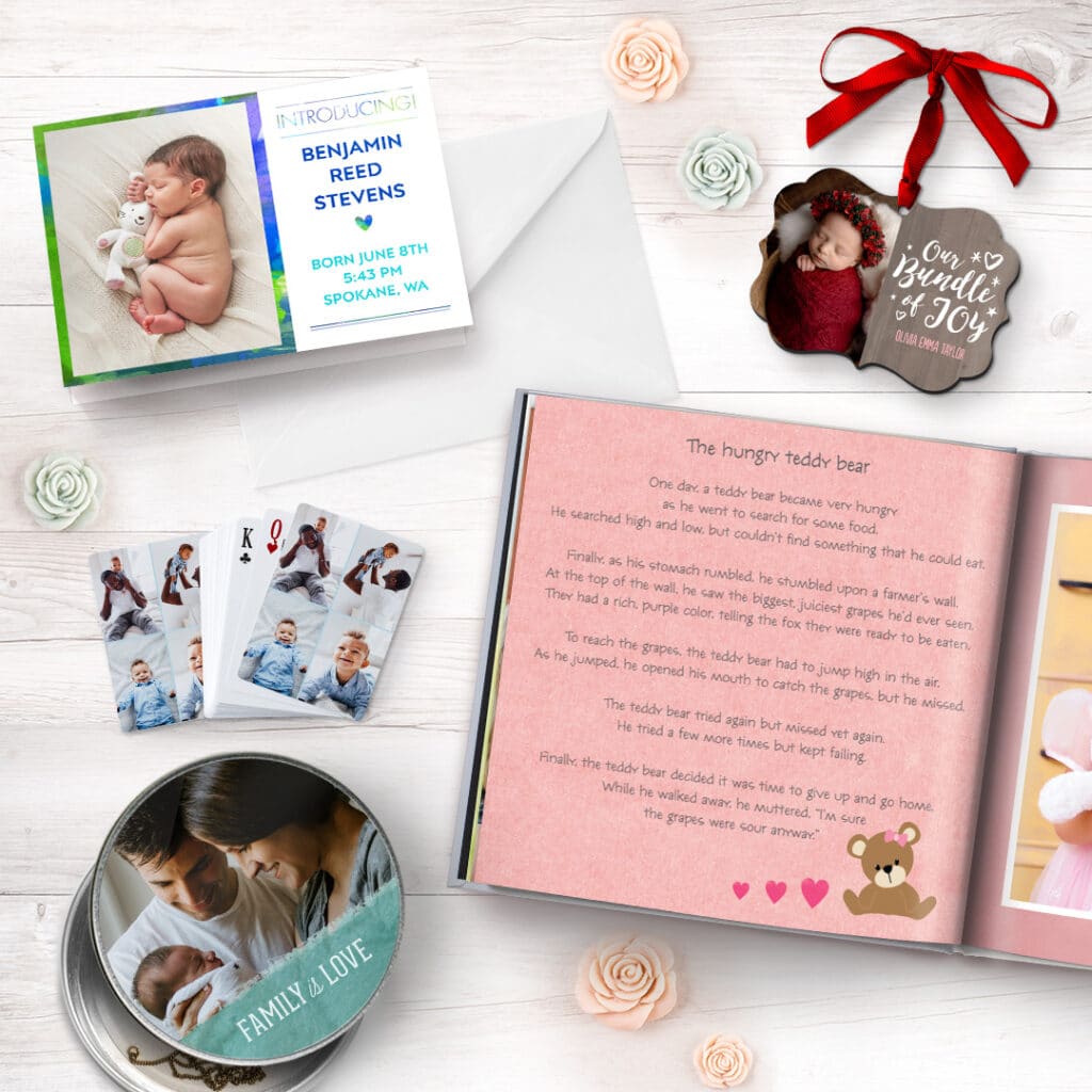 Variety of custom baby cards + gifts on a white surface with roses