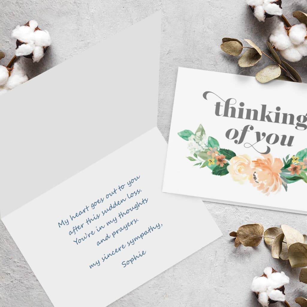 A lovely 'thinking of you' sympathy card presented on a grey surface with cotton flowers