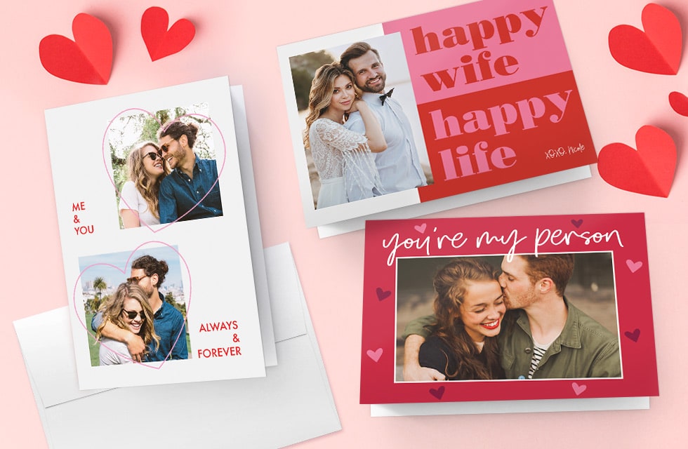 A selection of new Valentine's day cards presented on a pink surface with red paper hearts