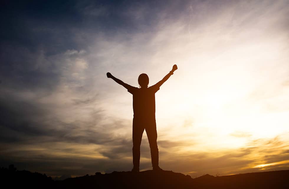 A beautiful sunset photo of a person with their arms outstretched