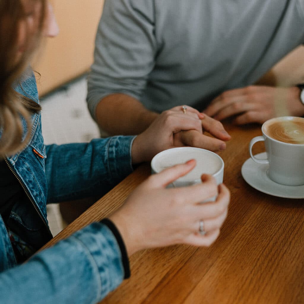 close up of people holding hands while having a coffee