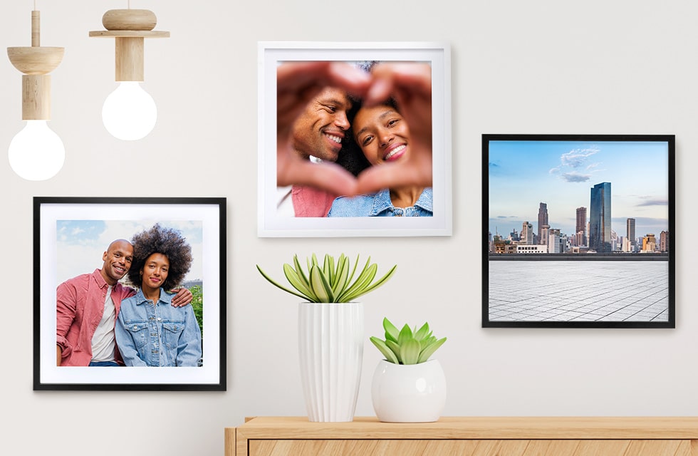 Framed Photo Tiles hung on a wall in front of a console table with plants